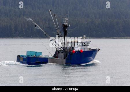 Imbarcazione commerciale da pesca - peschereccio da traino nell'oceano Pacifico con toutains in background. Juneau , Alaska Foto Stock