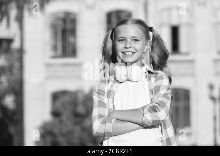 piccola ragazza casual stile outdoor. vacanza primaverile appena iniziata. la sua playlist estiva preferita. bambino ascolta musica. ragazzo sorridente che ascolta audiolibro. ragazza felice scuola indossare auricolari. scuola superiore. Foto Stock