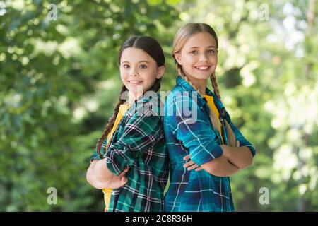 Studenti felici. Migliori amici della scuola. Concetto di amicizia. Le ragazze piccole indossano una camicia a scacchi. Moda casual per bambini. Felicità infantile. Giornata felice per bambini. Trascorrete del tempo e divertitevi insieme. Foto Stock