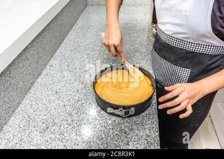 Mani che versano la torta finita nella muffa di casa Foto Stock