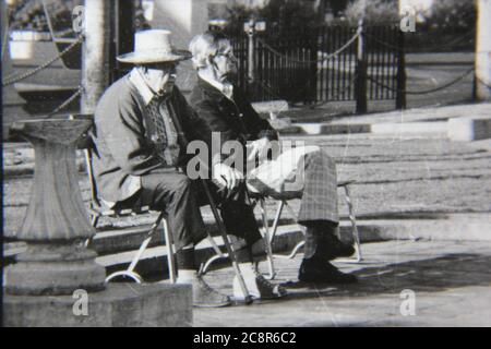 Bella fotografia in bianco e nero degli anni '70 di due vecchi amici che trascorrono il pomeriggio al parco pubblico locale. Foto Stock