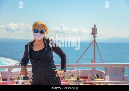 Donna in traghetto con maschera chirurgica durante Covid-19. Una donna turistica italiana viaggia sul Mar Tirreno fino all'Isola d'Elba in traghetto. Coronavirus Foto Stock