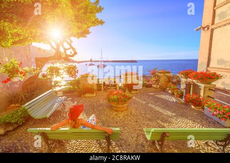 Elegante donna in rosso con cappello, Marciana Marina al tramonto, il fiorito vecchio quartiere Borgo al Cotone: Che significa VILLAGGIO DI COTONE. turistico in vacanza Foto Stock