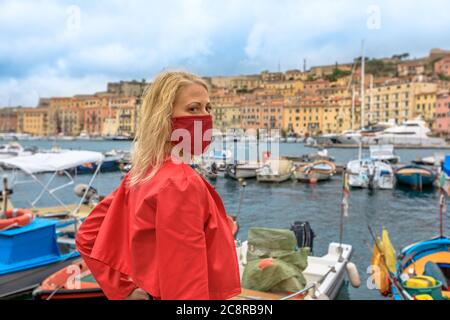 Isola d'Elba donna turistica con maschera chirurgica durante il Covid-19 nel porto di Portoferraio, Isola d'Elba. La donna turistica italiana viaggia sull'isola d'Elba Foto Stock