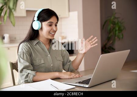 Felice studente indiano ragazza con cuffie e videochiamata a casa. Foto Stock