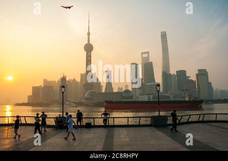 Una grande nave da carico sul fiume Huangpu di fronte allo skyline di Pudong di prima mattina preso dalla passeggiata Bund di Shanghai. Foto Stock