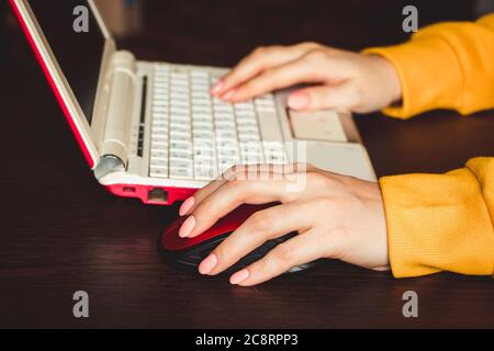 Giornata internazionale dei mancini. La donna di affari lavora con un laptop a casa e tiene un mouse del calcolatore nella sua mano sinistra. Foto Stock