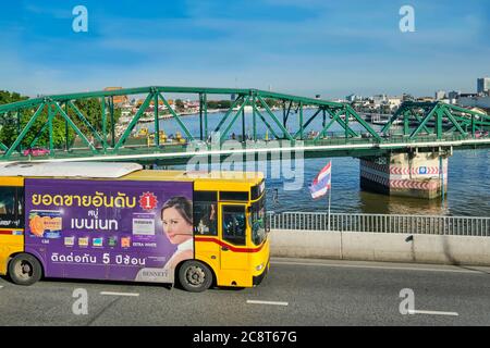 Un autobus giallo della città che attraversa il ponte Somdet Phra Pokklao, con Saphan Phut (Ponte Memoriale) e il fiume Chao Phraya nel b/g; Bangkok, Thailandia Foto Stock