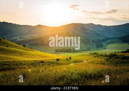 Mattina soleggiata in montagna. Tramonto sulle montagne. Paesaggio estivo in montagna. Strada di montagna serpentina. Bella composizione paesaggistica. Foto Stock