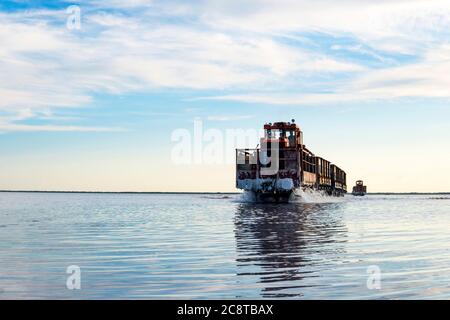 il treno viaggia dall'acqua. Sale estratto nel lago Burlin. Altai. Russia. Bursolith. Il vecchio treno corre sulla ferrovia posta in acqua attraverso il lago salato. Foto Stock