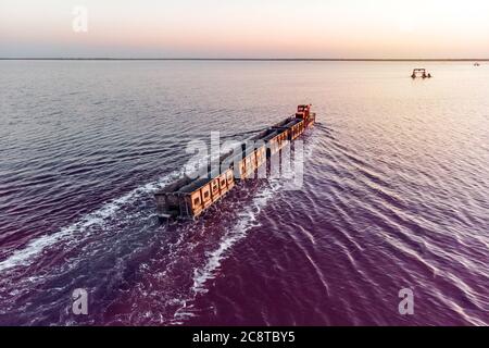 il treno viaggia dall'acqua. Sale estratto nel lago Burlin. Altai. Russia. Bursolith. Il vecchio treno corre sulla ferrovia posta in acqua attraverso il lago salato Foto Stock