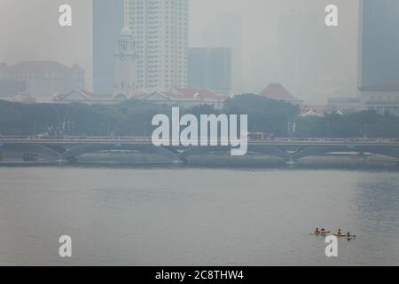 Quattro studenti in canoa sull'acqua durante l'inquinamento da foschia, le particelle d'aria possono causare rischi per la salute delle persone in città. Singapore, Sud-est asiatico, Foto Stock