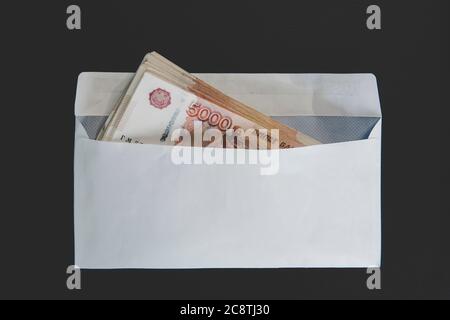 Grandi tagli di 5000 rubli in una busta bianca. Mano dell'uomo tiene una busta con soldi. Il concetto di corruzione e di corruzione Foto Stock