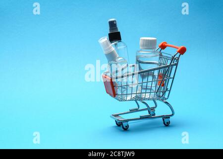 Protezione del virus di corona concetto di igiene - alcool mano disinfettante liquido nel carrello carrello troplley su sfondo blu. . Lavare a mano nel cestello Foto Stock