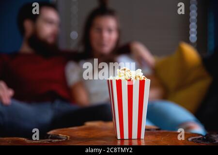 Una giovane coppia innamorata guardando la televisione di notte romantica data notte sdraiata sul divano mangiare popcorn Foto Stock