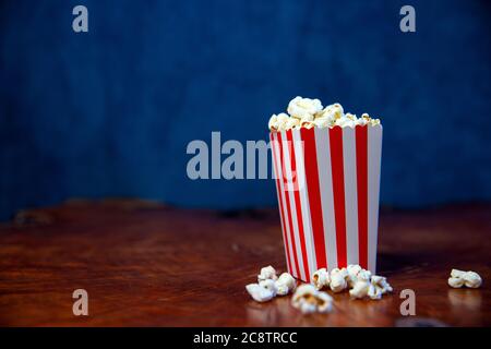 Popcorn in scatola di cartone a righe retrò rosso e bianco per il cinema su tavolo di legno Foto Stock