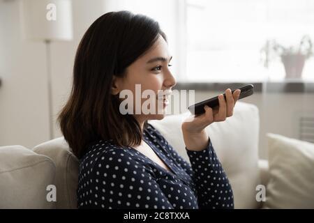 Ragazza asiatica attiva assistente vocale sul cellulare Foto Stock