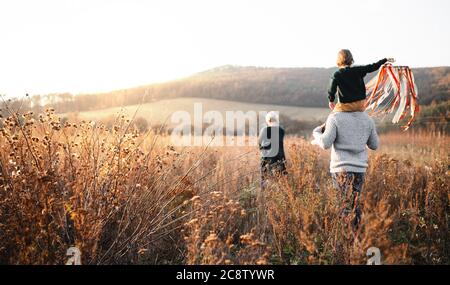 Vista posteriore della famiglia con piccola figlia su una passeggiata nella natura autunno. Foto Stock