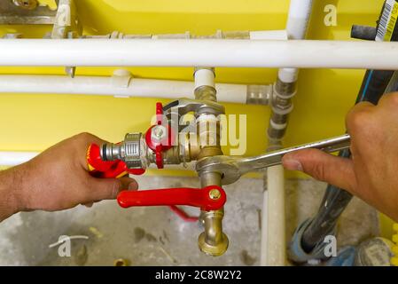 collegamento di raccordi idraulici con chiavi. L'idraulico assembla un nuovo collegamento dell'acqua al lavello. Foto Stock