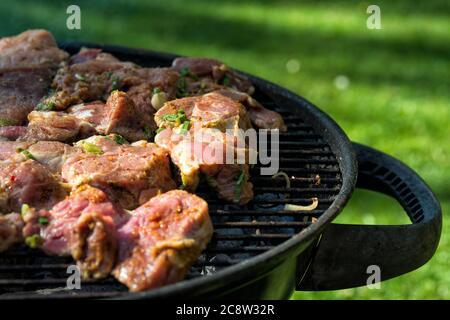 Bistecche fresche grigliate all'aperto sulla griglia rotonda barbecue Foto Stock