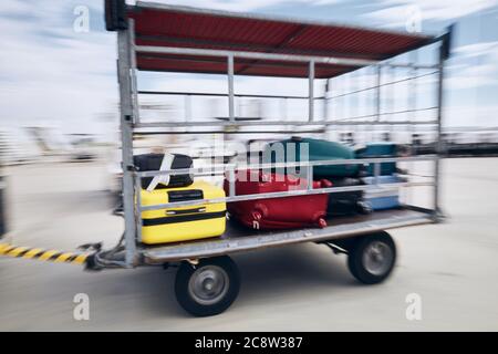 In aereo. Valigie nel rimorchio bagagli in movimento offuscato all'aeroporto. Foto Stock