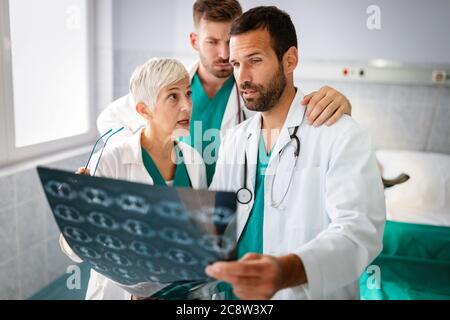 Medici che discutono la diagnosi del paziente guardando i raggi X in un ospedale Foto Stock