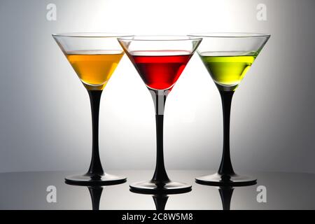 Bevande colorate in bicchieri martini, cocktail con liquori arancioni, rossi e verdi Foto Stock