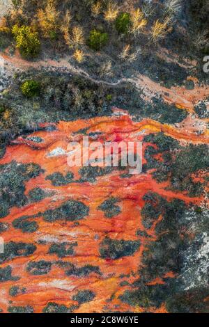 Gant, Ungheria - veduta aerea del drone orizzontale della miniera abbandonata di bauxite con colori caldi rosso e arancio e alberi al tramonto. Bauxite rossa Foto Stock