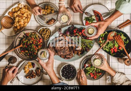 La gente che festeggiando al barbecue festa con carne, insalate, acqua di limone Foto Stock