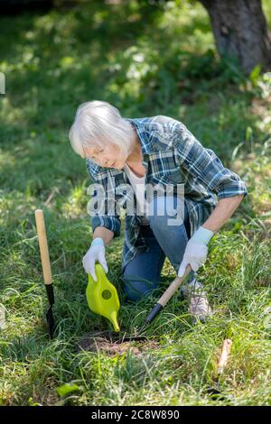 Donna anziana che si prende cura del suo orto Foto Stock