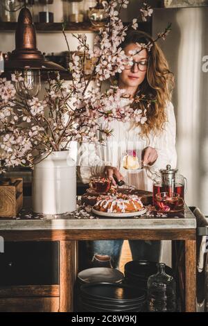 Donna che serve dolci senza glutine fatti in casa vicino rami fiorenti Foto Stock