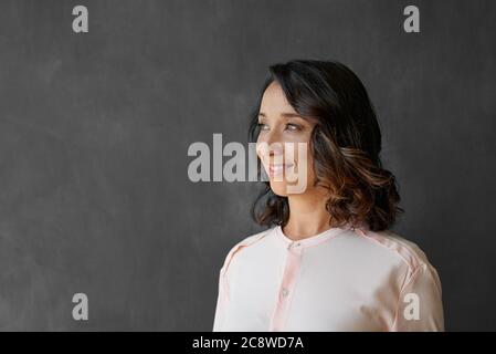 Giovane donna d'affari asiatica sorridente mentre si è in piedi da sola davanti ad una lavagna vuota in un ufficio Foto Stock