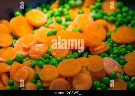 piselli a cottura rapida con fette di carota nella padella Foto Stock