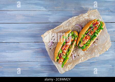 Hot dog fatto in casa con salsiccia, insalata, carota, cetriolo e pomodoro su sfondo di legno Foto Stock