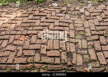 vecchia passeggiata laterale in mattoni che ha bisogno di alcune riparazioni Foto Stock