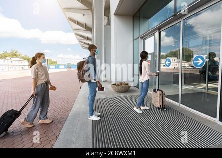 Aeroporto Social Distancing. I passeggeri indossano maschere che si trovano in piedi a turno all'ingresso del terminal Foto Stock