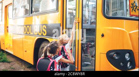 Le studentesse con gli zaini entrano nel bus scolastico, tornano a scuola Foto Stock