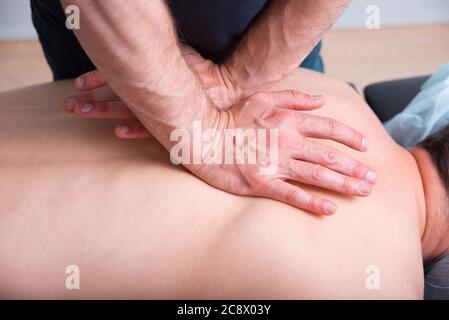 Fisioterapista sta facendo un massaggio profondo su una schiena mans. Foto Stock