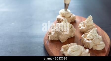 Il processo di creazione di Pavlova dessert, decorazione della meringa con crema dalla borsa culinaria Foto Stock