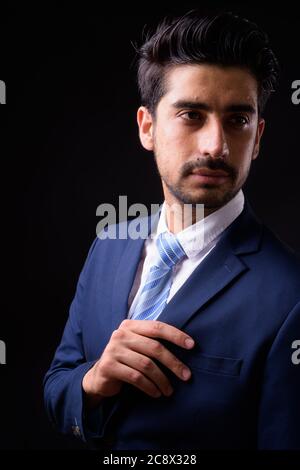 Giovane bell'uomo d'affari persiano sopportato contro sfondo nero Foto Stock