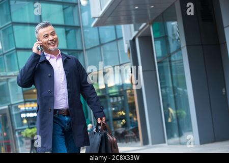 Trasporto di una borsa sul commercio del telefono in uomini di mezza età Foto Stock