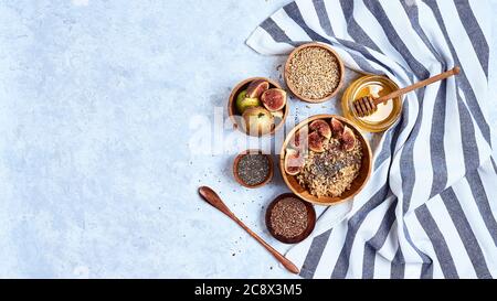 Ingredienti salutari per la colazione e la colazione, farinata d'avena con fichi, semi di lino e di cia, miele. Vista dall'alto, disposizione piatta Foto Stock