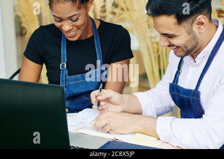 Felici i giovani proprietari di caffè che controllano le fatture e altri documenti finanziari quando fanno la relazione per l'ufficio di imposta Foto Stock
