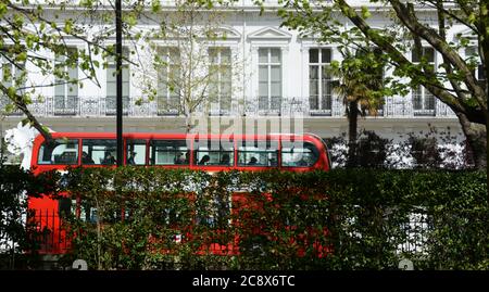 Autobus a due piani rosso di Londra nel cuore di Kensington su viale con bandiere di nazioni. Foto Stock