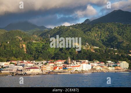 La città di Roseau sull'isola di Dominica vista dal mare con un paesaggio di colline boscose oltre e nuvole in un cielo blu sopra, i Caraibi Foto Stock