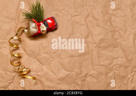 Il carrello del raccoglitore del giocattolo trasporta una borsa dei regali e un albero di Natale. Vista dall'alto, a sinistra su uno sfondo marrone di carta. Foto Stock