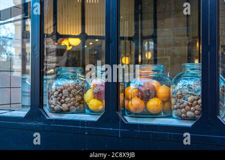 vaso di vetro con frutta biologica sul vetrin del negozio. limone biologico, melograno, arancia in un vaso di vetro Foto Stock