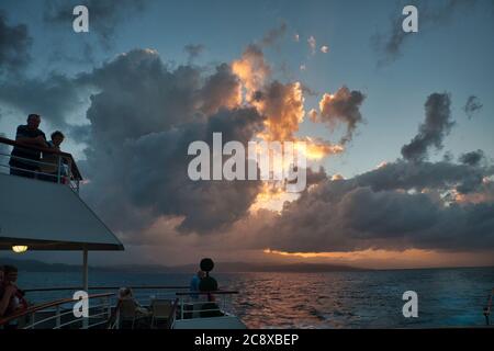 Tramonto spettacolare al largo della costa della Giamaica, Caraibi, con la gente su una nave da crociera silhouette in primo piano Foto Stock