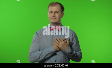 Bell'uomo dal cuore aperto che dà dal cuore, gesturing prenderlo gratuitamente, cercando gentilmente, condividendo la cura dell'amore, concetto di generosità. Ritratto di ragazzo che posa isolato su sfondo chiave chroma Foto Stock