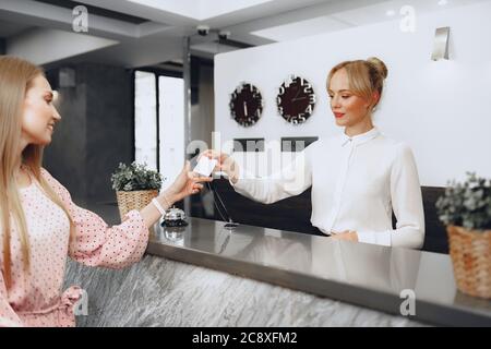 Giovane ospite dell'hotel che riceve la chiave di accesso dall'addetto alla reception Foto Stock